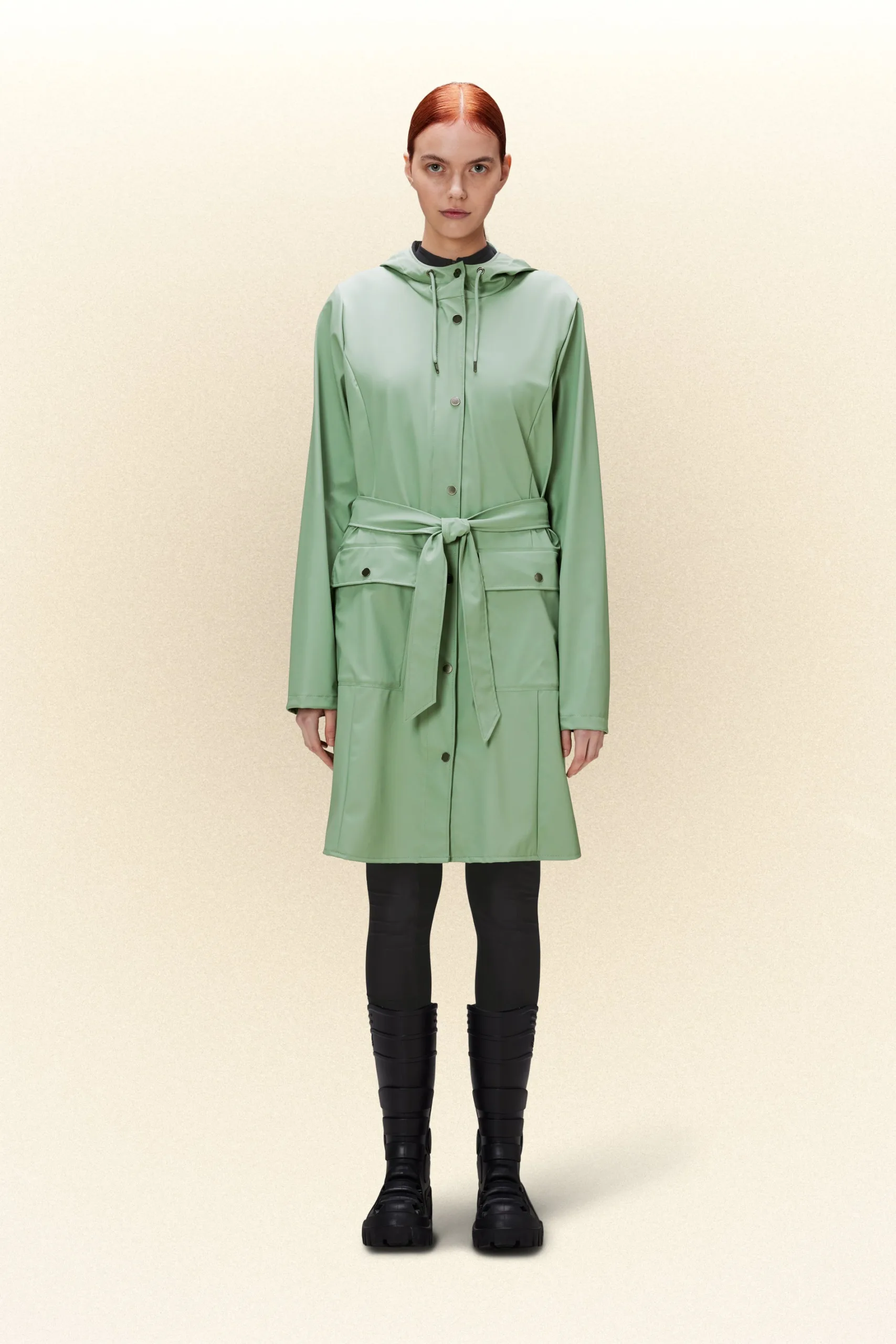A woman in a green raincoat standing on a white background.