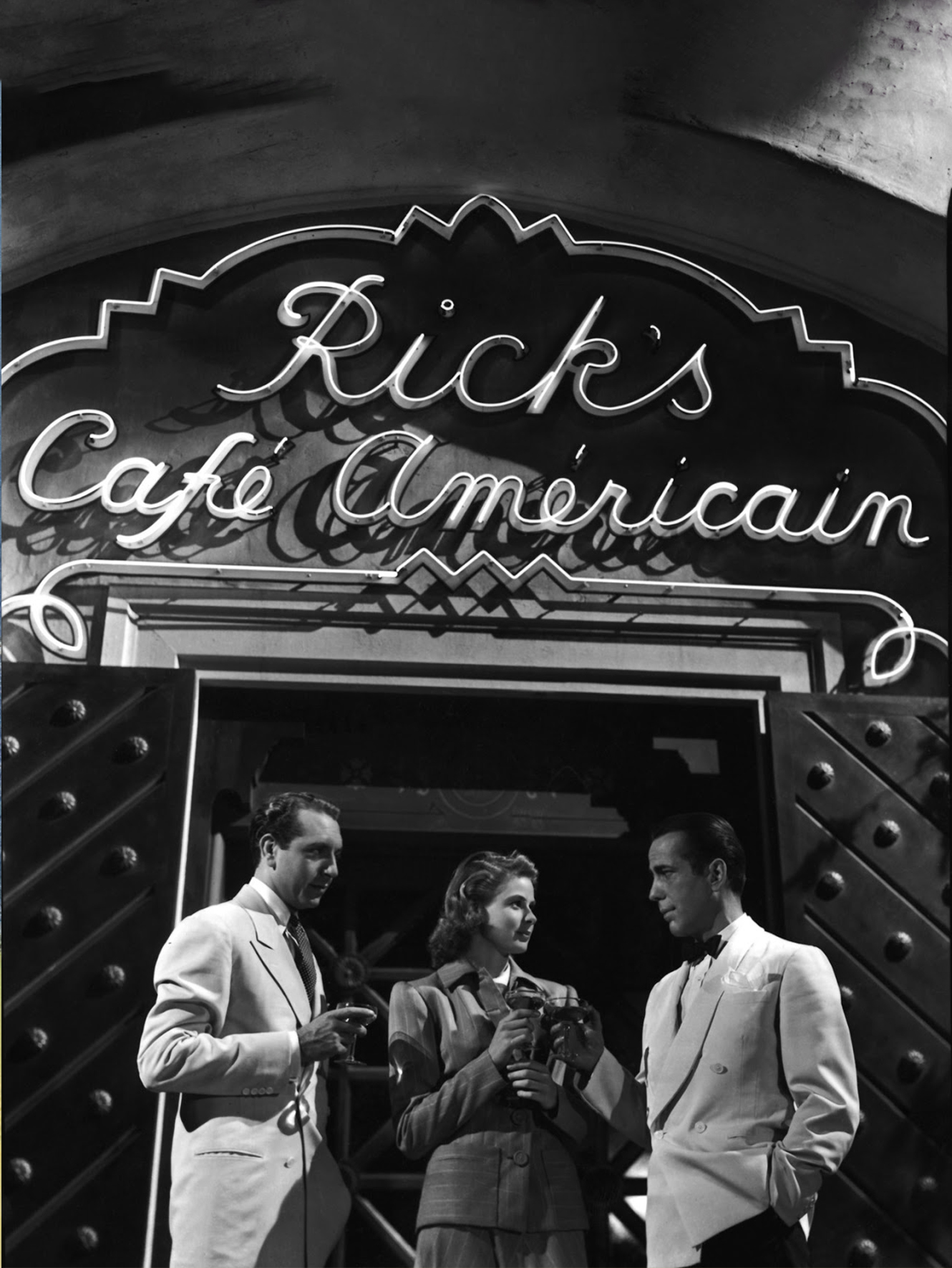 Three people, including Ingrid Bergman, standing in front of Rick's Cafe American.