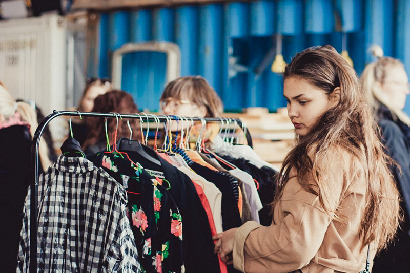 A woman browsing clothes at a Copenhagen fashion event.