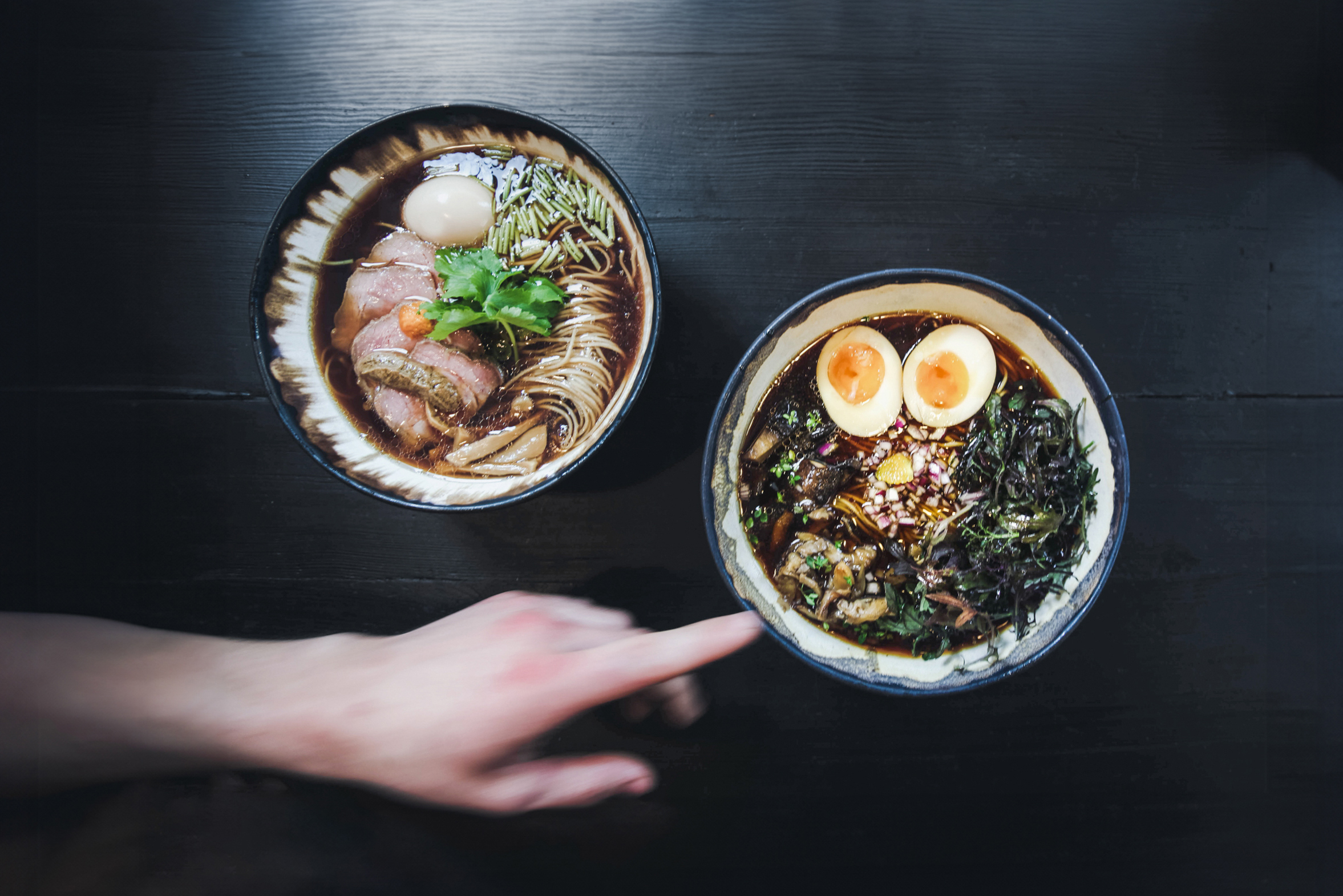 A hand pointing at bowls of food.