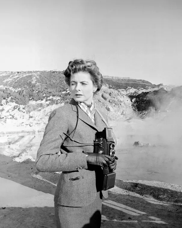 Ingrid Bergman holding a camera in front of a hot spring.