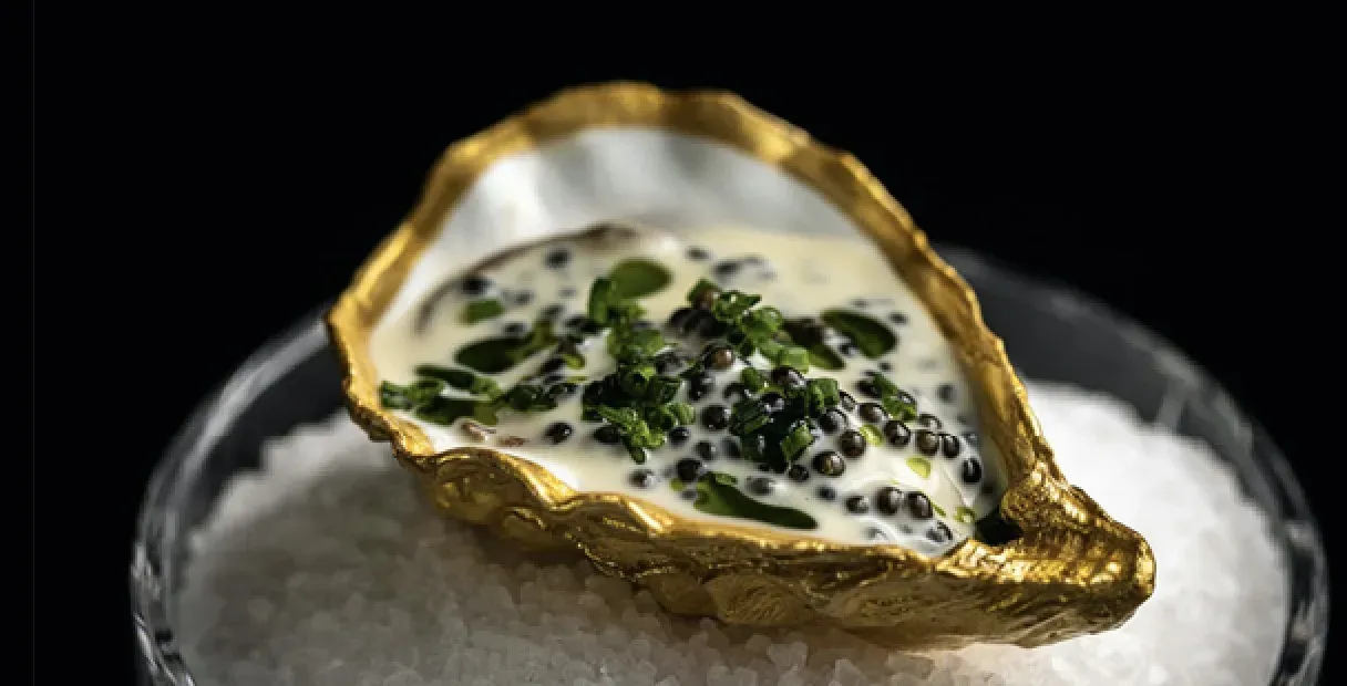 A gold oyster shell on a glass of water in Copenhagen.