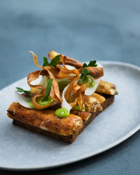 A white plate with a piece of bread on it, found in Copenhagen restaurants.