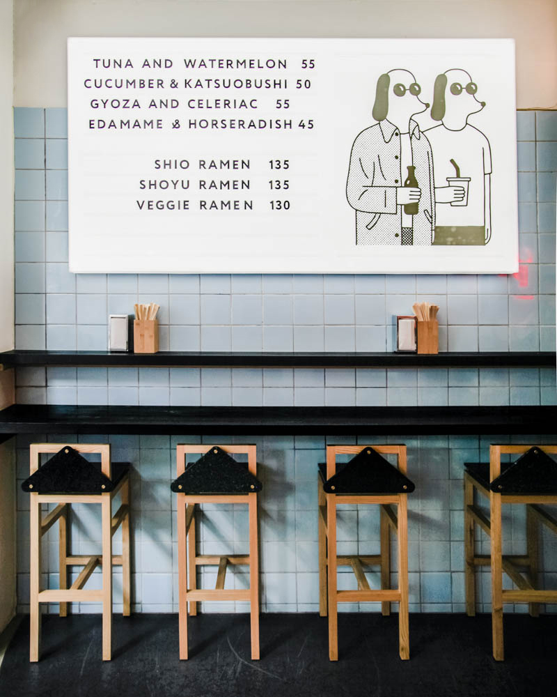 A Copenhagen restaurant with stools and a sign on the wall.