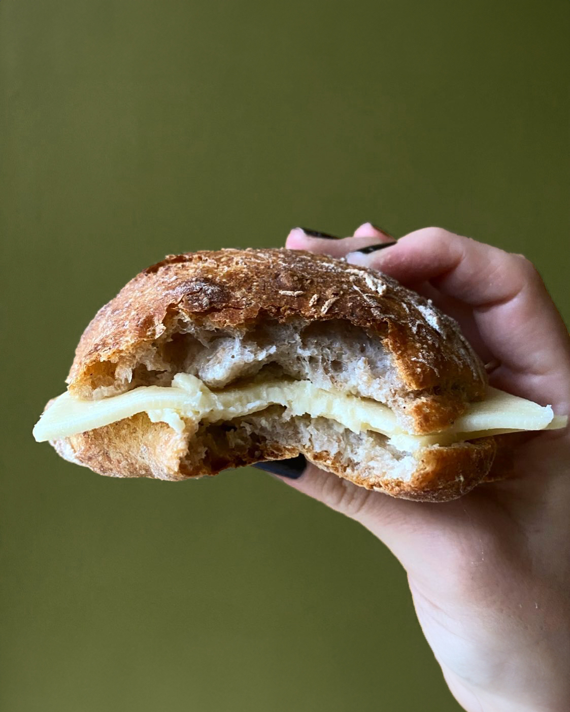 A person holding up a sandwich with cheese on it at a Copenhagen restaurant.